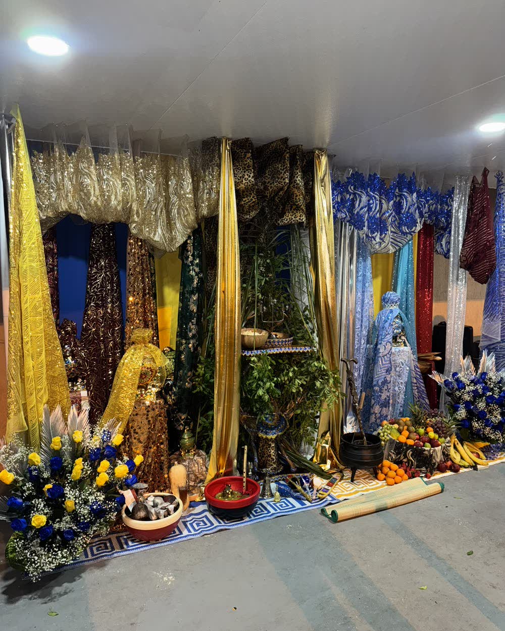 Trono en azul y oro con flores y ofrendas